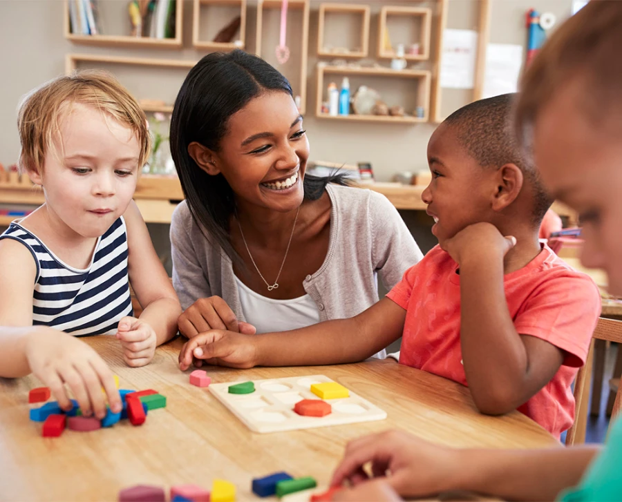 Teacher And Pupils Using Wooden Shapes In Montessori School
