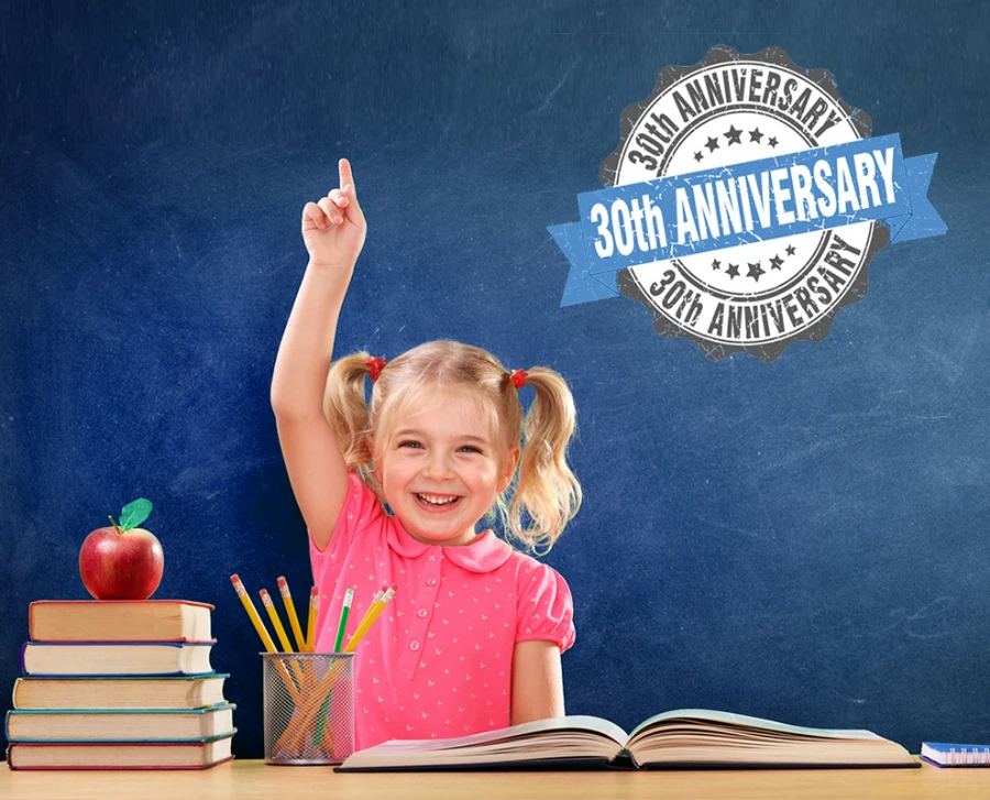 Little girl raising hand in front of blackboard
